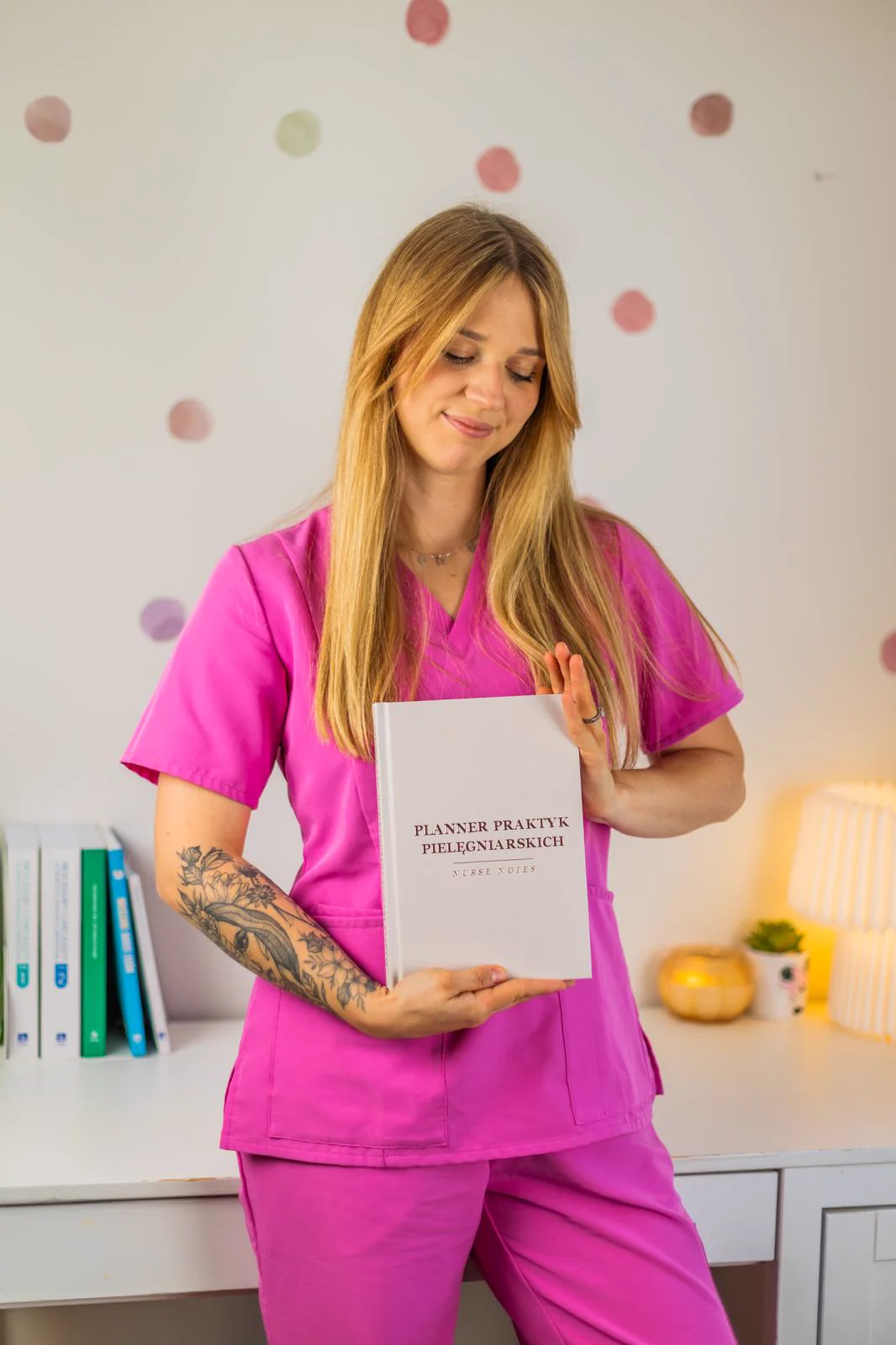 Karolina w stroju medycznym trzyma Planner Praktyk Pielęgniarskich